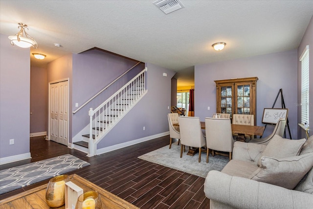 living room featuring a textured ceiling and dark wood-type flooring