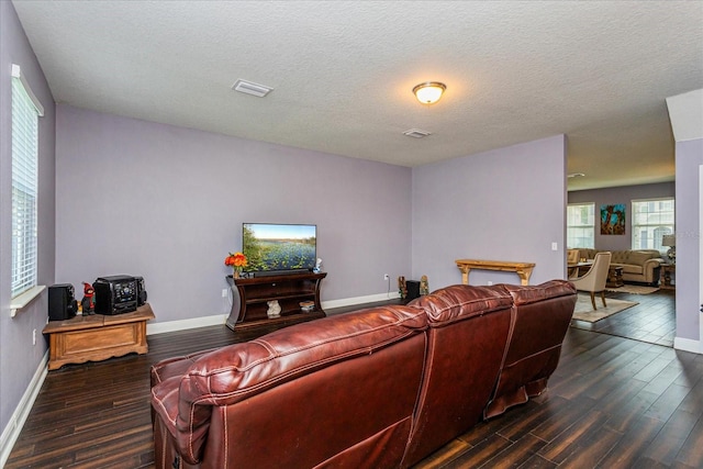 living room with a textured ceiling, dark wood-type flooring, and a wealth of natural light