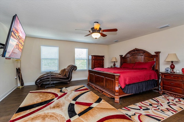 bedroom with a textured ceiling, dark hardwood / wood-style floors, and ceiling fan