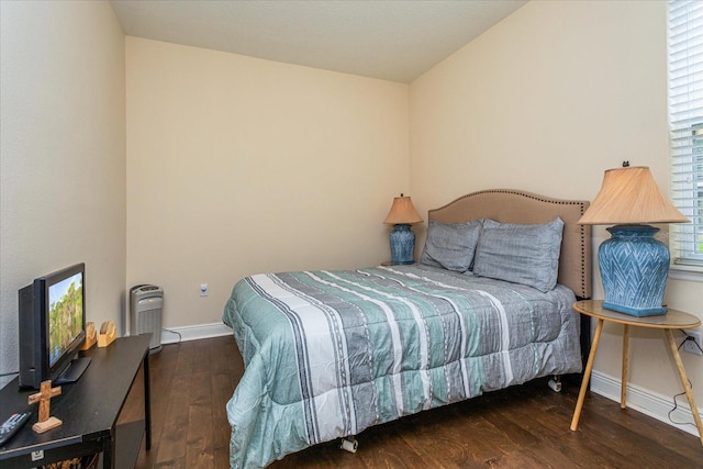 bedroom with multiple windows and dark hardwood / wood-style floors