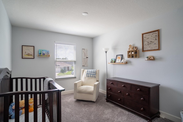 carpeted bedroom featuring a textured ceiling and a nursery area