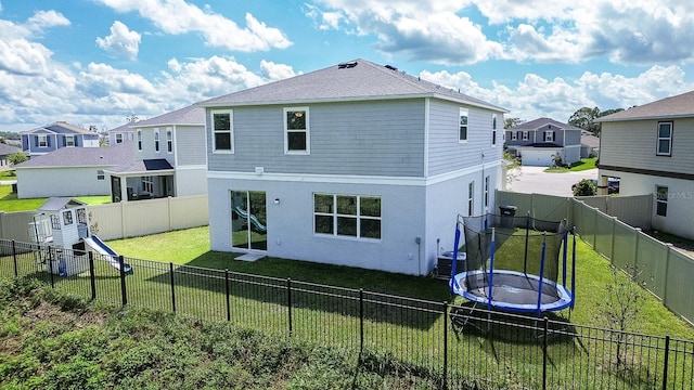 back of property featuring central AC unit, a trampoline, and a lawn