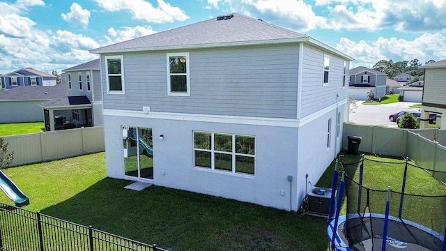 rear view of property featuring a lawn and cooling unit