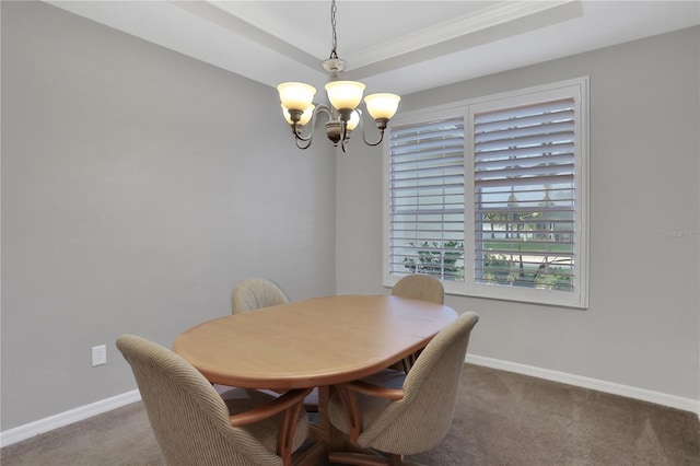 dining room featuring a chandelier, a raised ceiling, carpet flooring, and crown molding