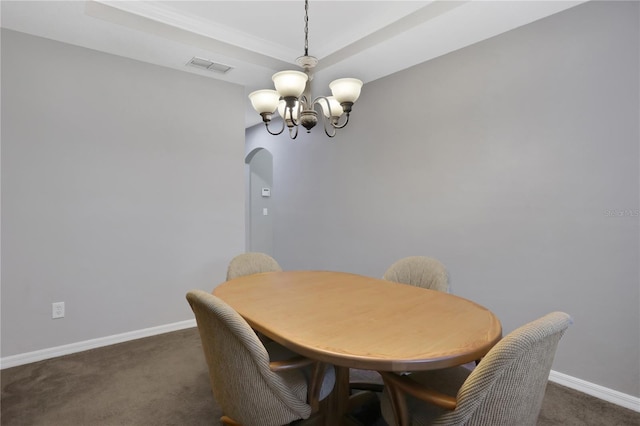 carpeted dining room with a notable chandelier and a raised ceiling