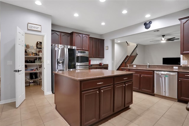 kitchen with appliances with stainless steel finishes, light tile patterned flooring, a kitchen island, and ceiling fan