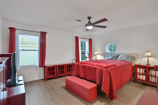 bedroom with ceiling fan, light hardwood / wood-style floors, and multiple windows