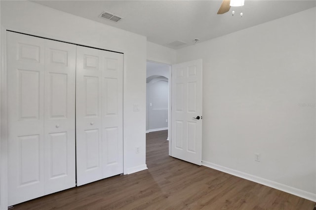 unfurnished bedroom with dark hardwood / wood-style floors, ceiling fan, and a closet