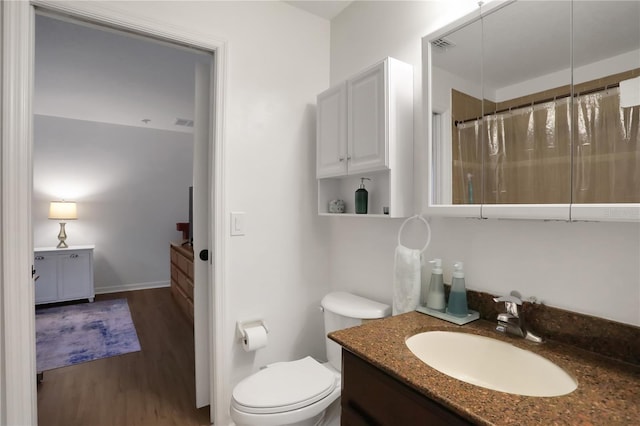 bathroom with wood-type flooring, vanity, walk in shower, and toilet