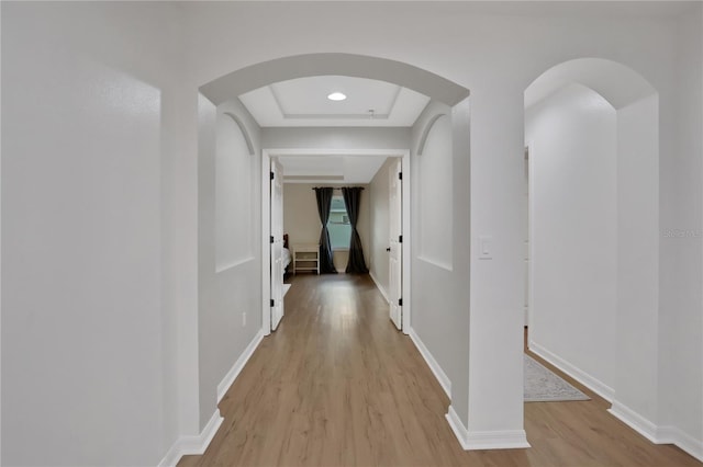 hall featuring a raised ceiling and light hardwood / wood-style floors