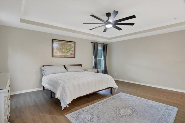 bedroom featuring ceiling fan, a raised ceiling, and dark hardwood / wood-style floors