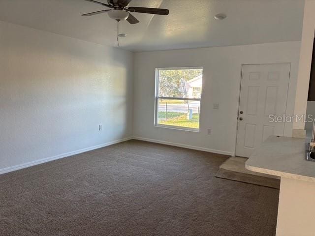 empty room featuring dark colored carpet and ceiling fan