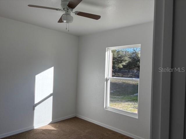 spare room featuring dark colored carpet and ceiling fan