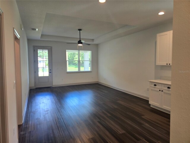 spare room featuring a tray ceiling, ceiling fan, and dark hardwood / wood-style floors