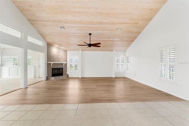 unfurnished living room with a large fireplace, ceiling fan, wooden ceiling, and light wood-type flooring