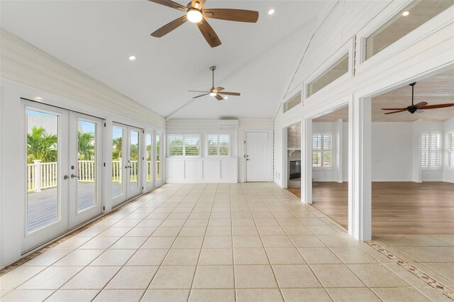 unfurnished sunroom with lofted ceiling, ceiling fan, plenty of natural light, and french doors