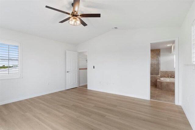 unfurnished bedroom featuring light hardwood / wood-style flooring, lofted ceiling, ensuite bath, and ceiling fan