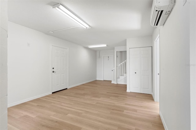 spare room featuring light wood-type flooring and an AC wall unit