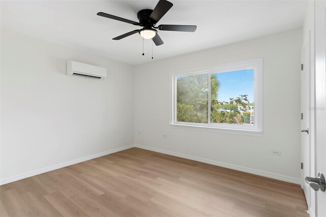 spare room with an AC wall unit, light hardwood / wood-style floors, and ceiling fan