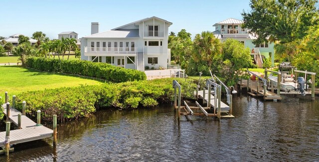 view of dock featuring a balcony, a water view, and a yard