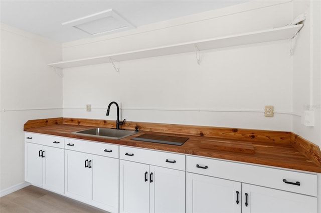 kitchen with light hardwood / wood-style floors, butcher block countertops, sink, and white cabinetry