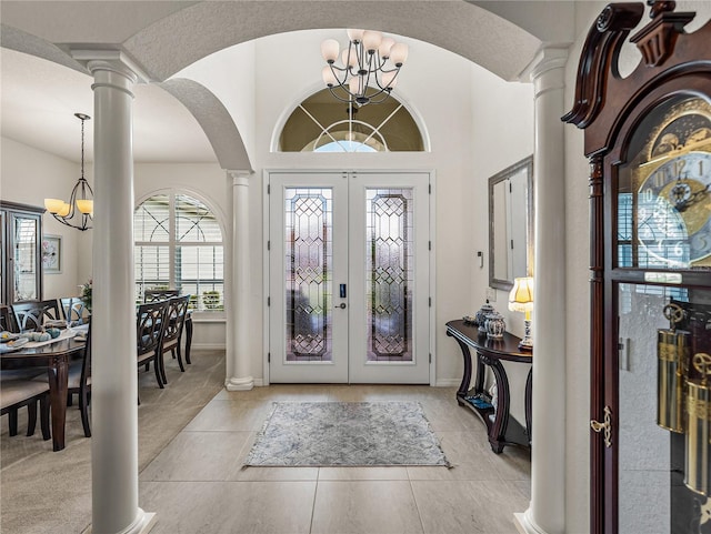 foyer with ornate columns, light tile patterned floors, french doors, and a notable chandelier