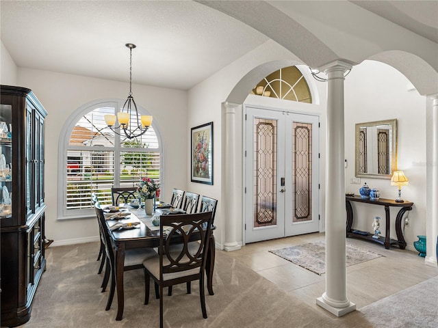 dining space with light carpet, a chandelier, french doors, and ornate columns