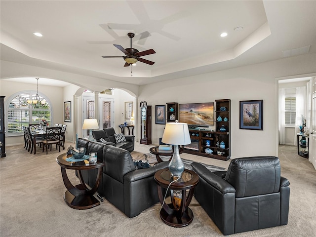 living room with a tray ceiling, ceiling fan, light colored carpet, and ornate columns