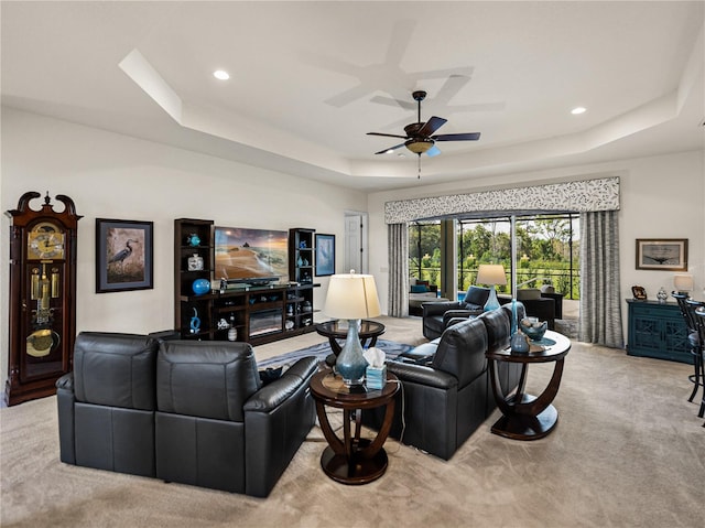 carpeted living room featuring a tray ceiling and ceiling fan