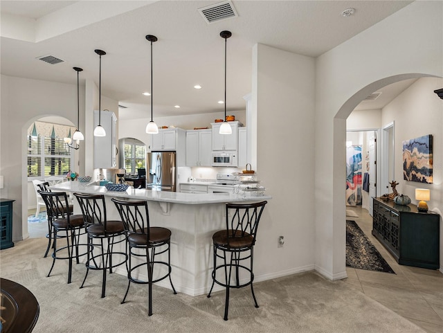 kitchen featuring hanging light fixtures, white appliances, light colored carpet, and white cabinets