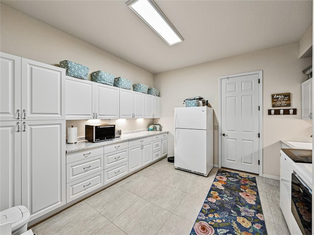 kitchen featuring white cabinets, light tile patterned floors, and white fridge