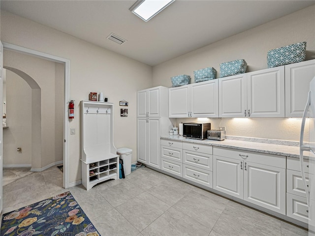 kitchen featuring light tile patterned floors and white cabinets