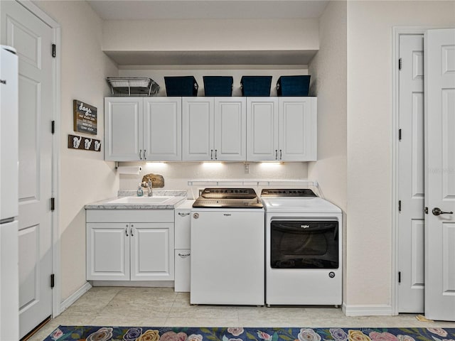 clothes washing area featuring light tile patterned floors, separate washer and dryer, cabinets, and sink