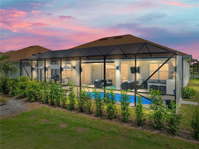 back house at dusk featuring a lanai, an outdoor living space, and a patio area