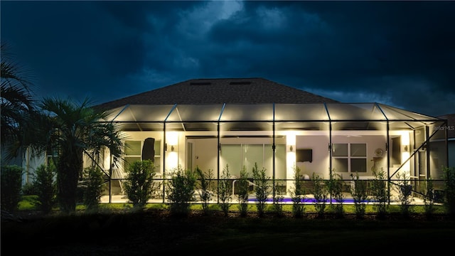 back house at night featuring a lanai