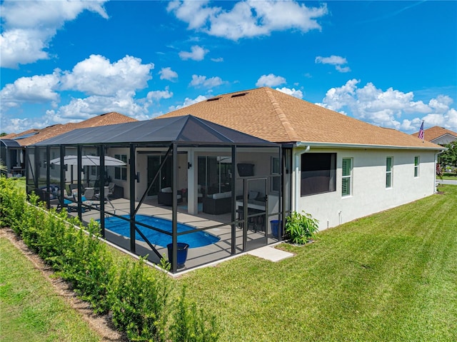 rear view of house with glass enclosure, a lawn, and a patio area