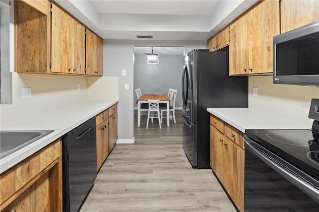 kitchen featuring hanging light fixtures, black appliances, and light hardwood / wood-style flooring