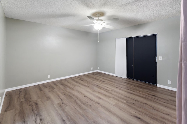 unfurnished bedroom with wood-type flooring, a textured ceiling, a closet, and ceiling fan