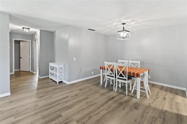 dining room with an inviting chandelier, hardwood / wood-style flooring, and a textured ceiling