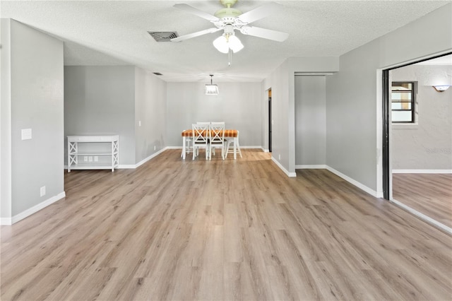 unfurnished dining area featuring a textured ceiling, light hardwood / wood-style floors, and ceiling fan