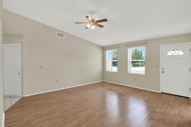 foyer entrance with light wood-type flooring, lofted ceiling, ceiling fan, and a textured ceiling