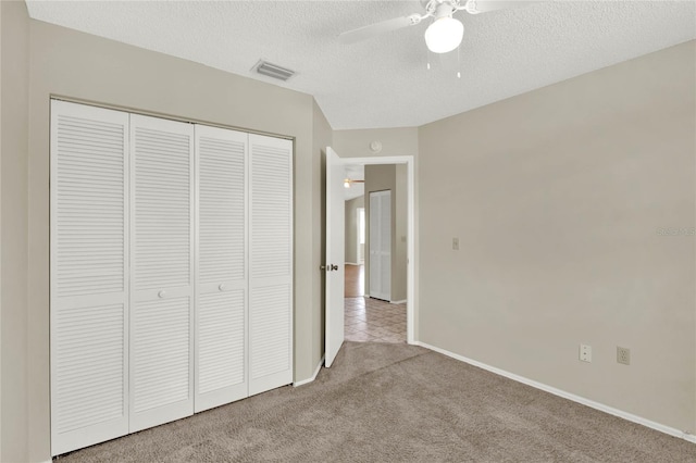 unfurnished bedroom featuring light carpet, a closet, ceiling fan, and a textured ceiling