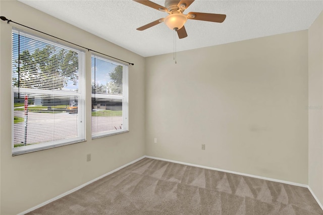 unfurnished room featuring a textured ceiling, ceiling fan, light colored carpet, and a wealth of natural light