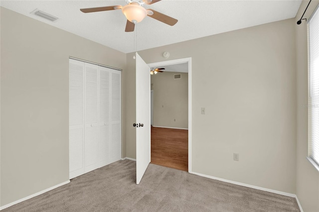 unfurnished bedroom with light carpet, a closet, and ceiling fan