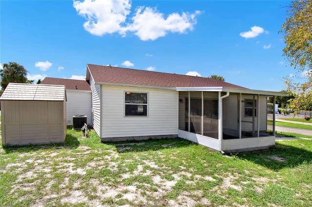 rear view of property with a sunroom, cooling unit, a shed, and a yard