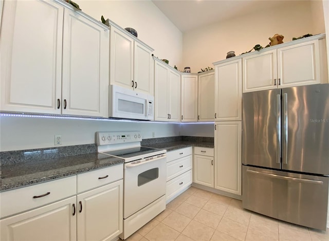 kitchen with white cabinets, white appliances, dark stone counters, and light tile patterned flooring