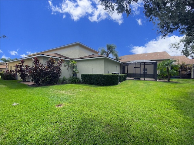 rear view of property featuring a lanai and a lawn