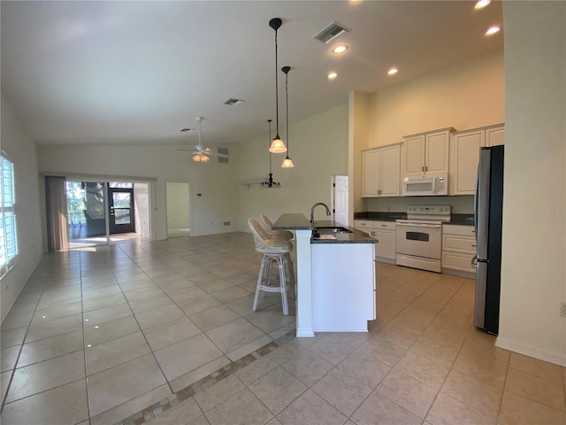 kitchen featuring a center island with sink, hanging light fixtures, sink, a breakfast bar area, and white appliances