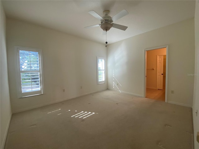 spare room featuring light carpet, ceiling fan, and plenty of natural light