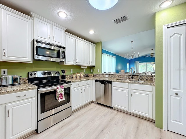 kitchen featuring vaulted ceiling, appliances with stainless steel finishes, white cabinetry, and sink